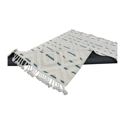Folded view of cream and blue hand-tufted wool rug showing its thick sculpted pile and tasselled ends