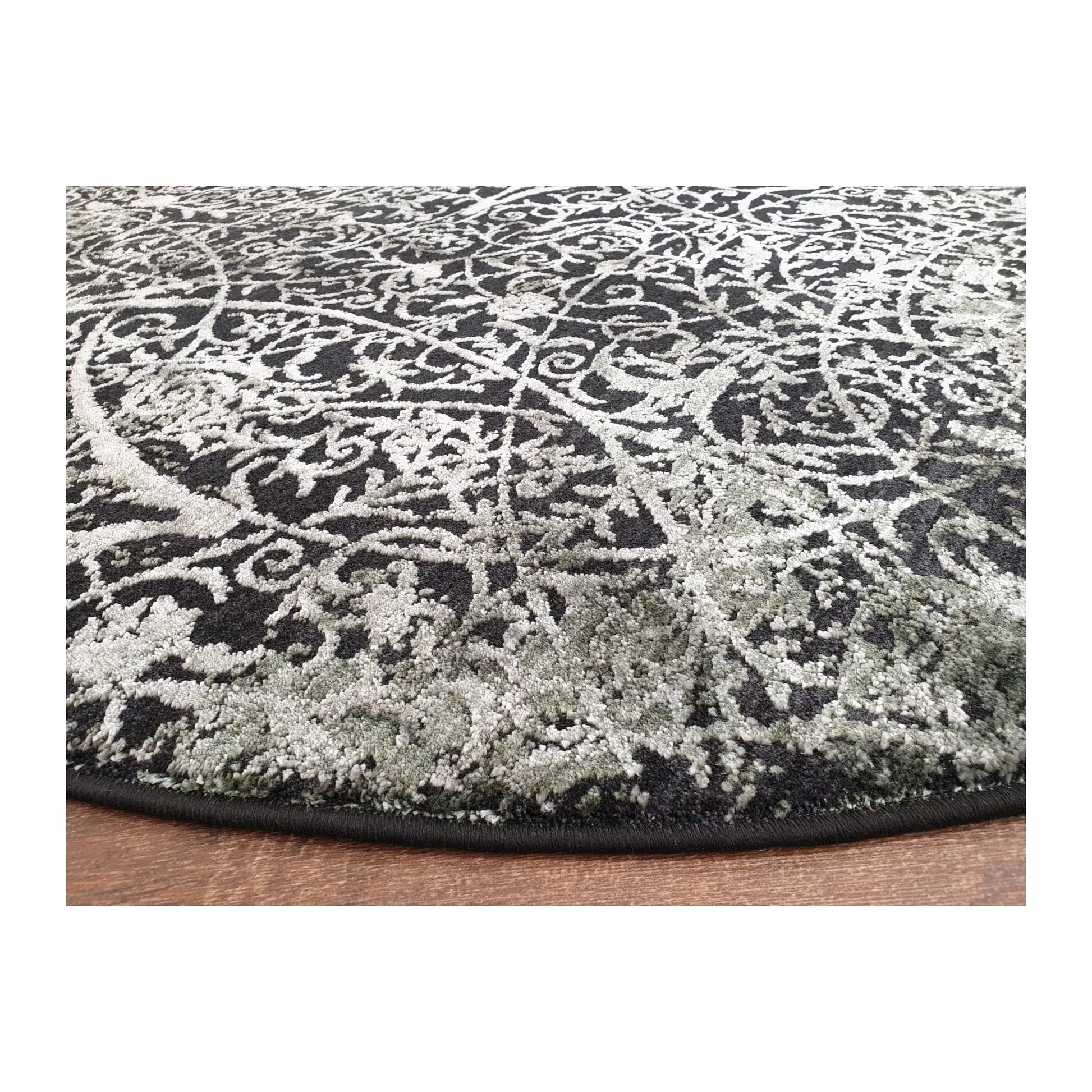 Low-angle close-up of emerald and charcoal round rug showing surface texture and patterned finish, 160 cm