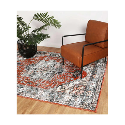 Estate Terracotta medallion rug styled with a leather chair and plant, showing its terracotta, ivory and charcoal pattern