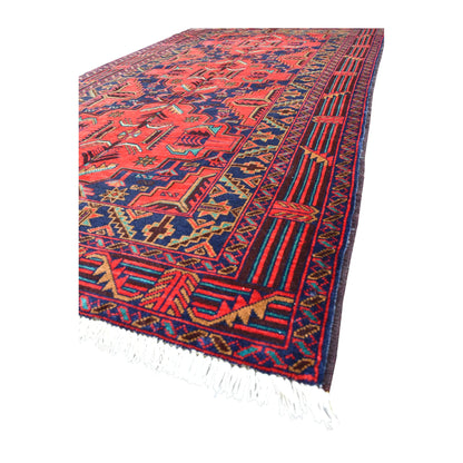 Angled view of fine Afghan Baluchi wool rug showing its dense red field, layered borders and pale fringe