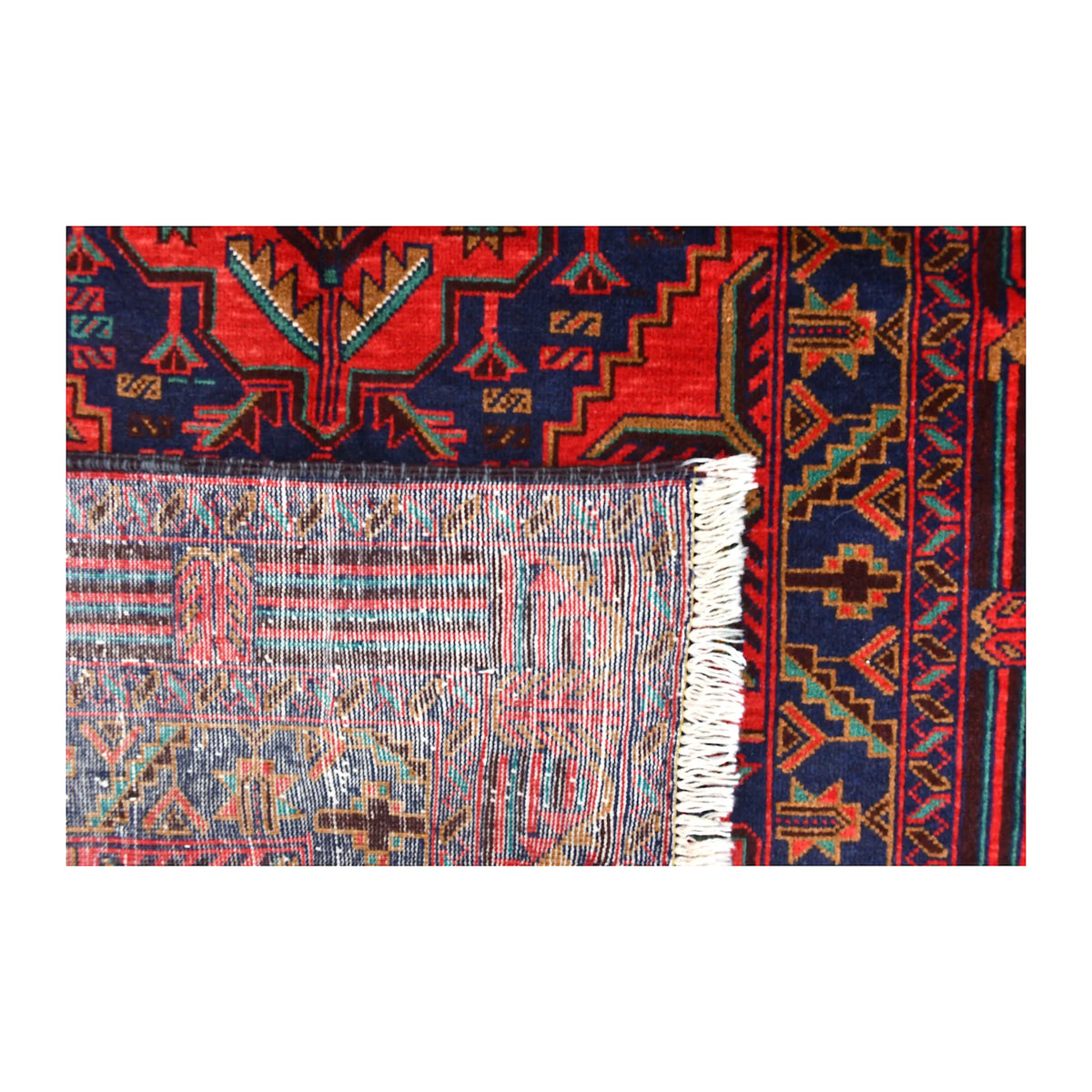 Folded-corner detail of Baluchi rug showing the reverse weave, floral-geometric front and pale fringe
