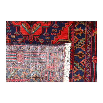 Folded-corner detail of Baluchi rug showing the reverse weave, floral-geometric front and pale fringe