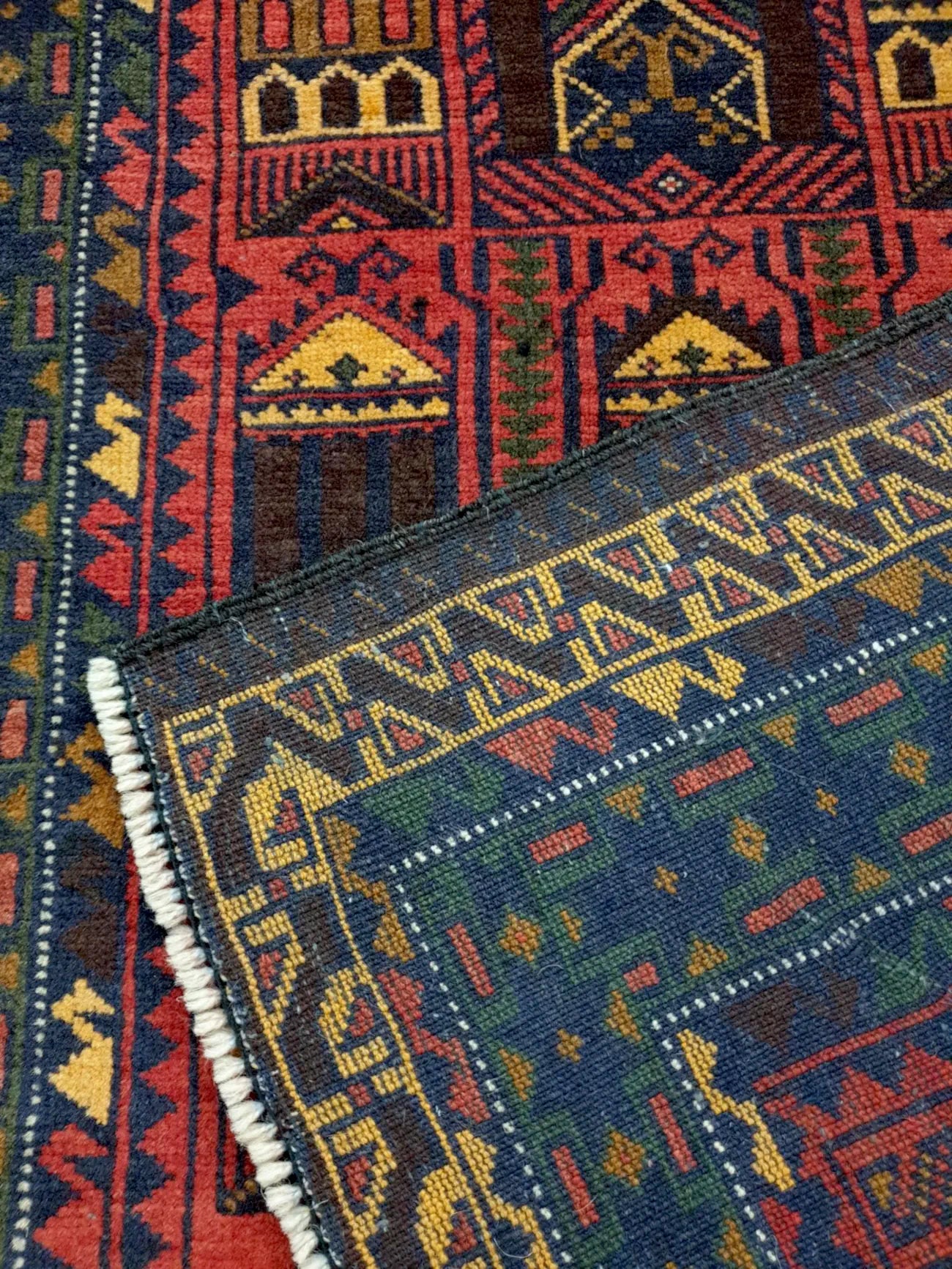 Fine Baluchi hand-knotted wool rug folded corner detail