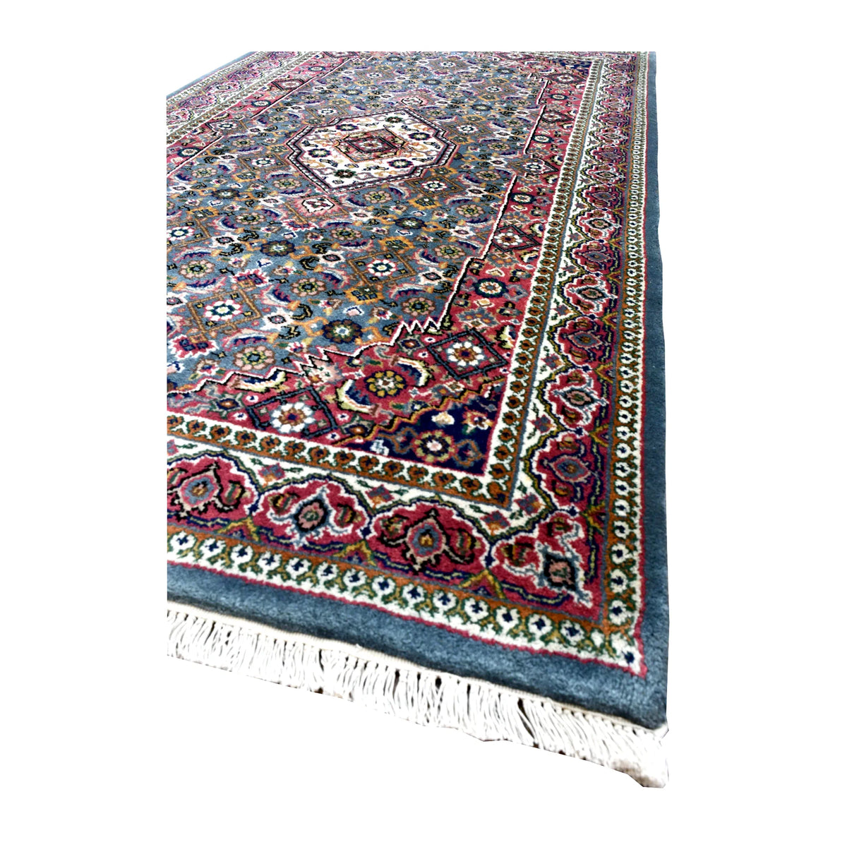 Angled detail of Fine Bidjar rug showing its blue-grey field, layered red floral borders and cream fringe