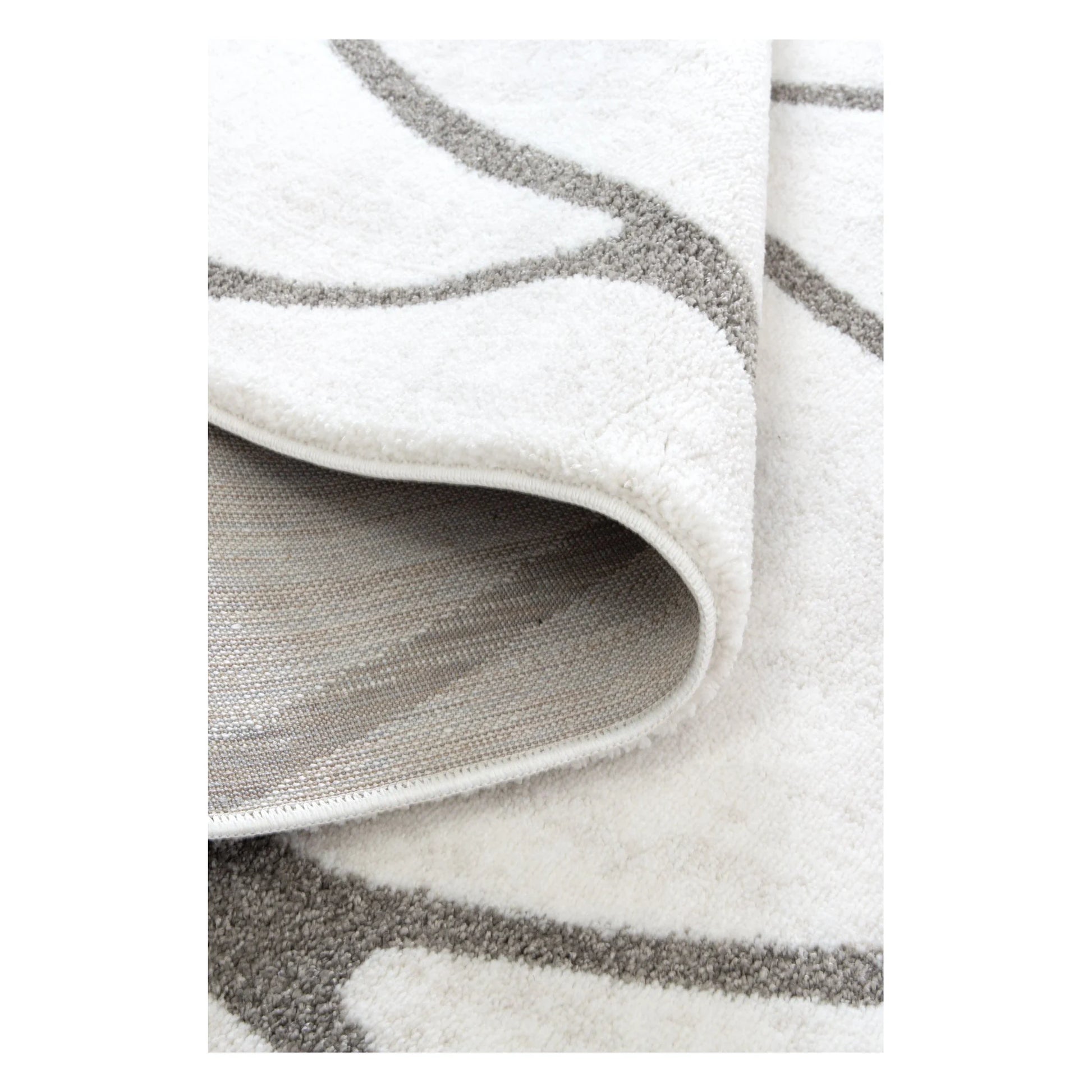 Folded Grace ivory grey trellis rug showing edge finish and flexible pile