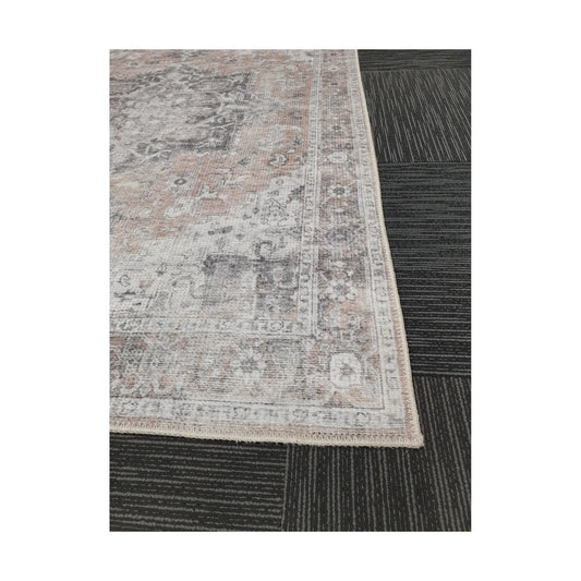 Close-up of grey blush cotton rug corner with faded ornamental border detail