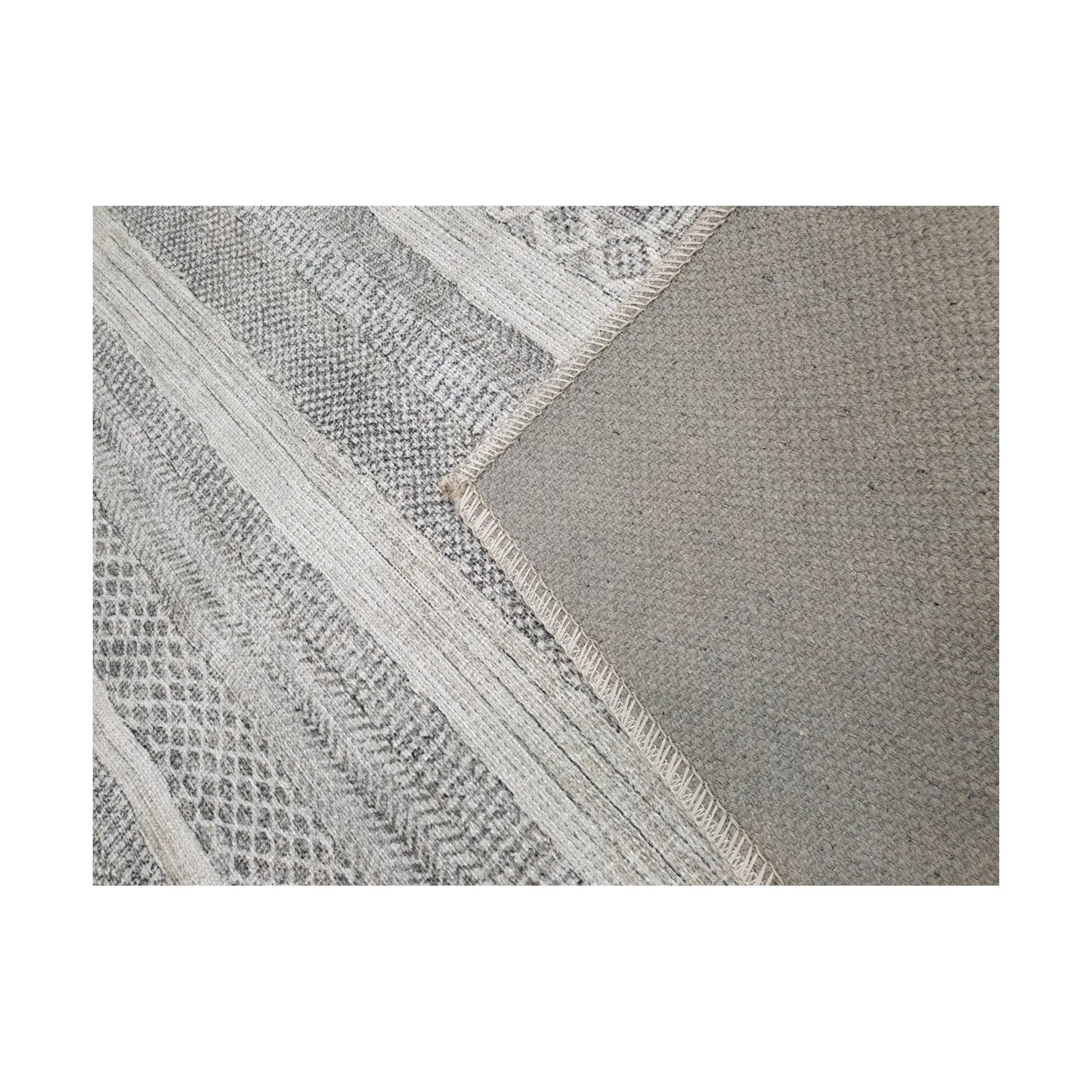 Close-up of grey ivory cotton rug corner with back and edge detail