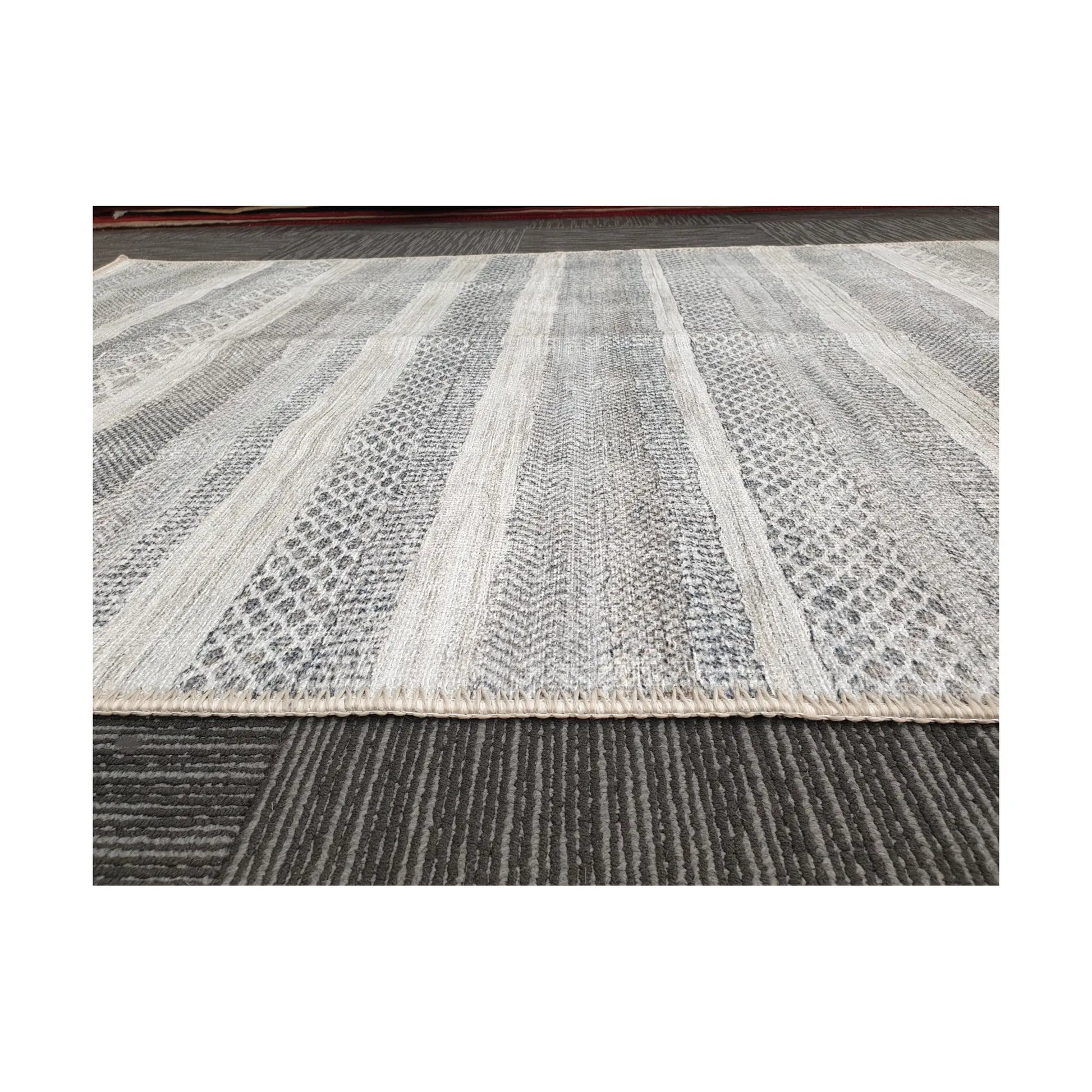 Low-angle view of grey ivory geometric stripe cotton rug edge and surface texture