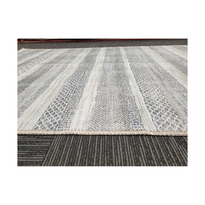 Low-angle view of grey ivory geometric stripe cotton rug edge and surface texture