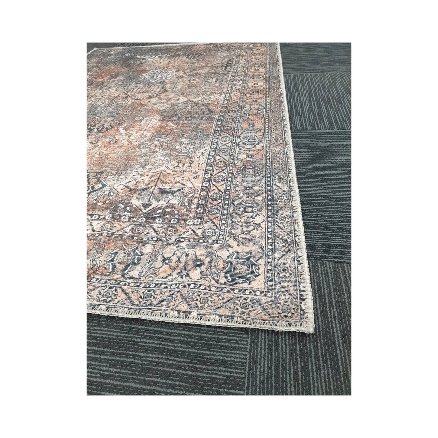 Close-up of grey rust cotton rug corner with faded ornamental border detail