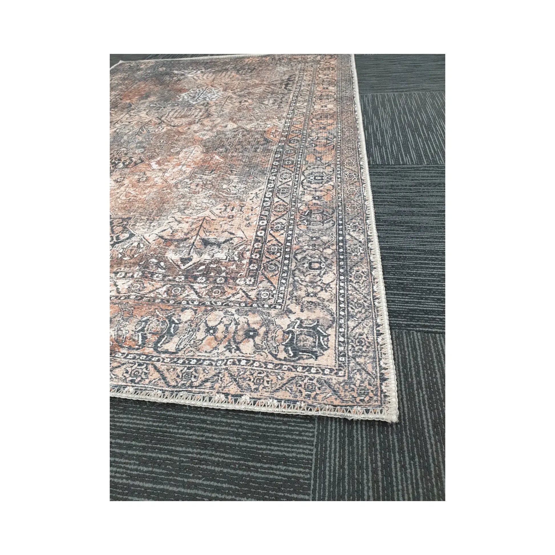 Close-up of grey rust cotton rug corner with faded ornamental border detail