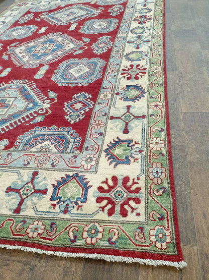 Close-up of red Kazak wool rug showing cream geometric weave and dense pile