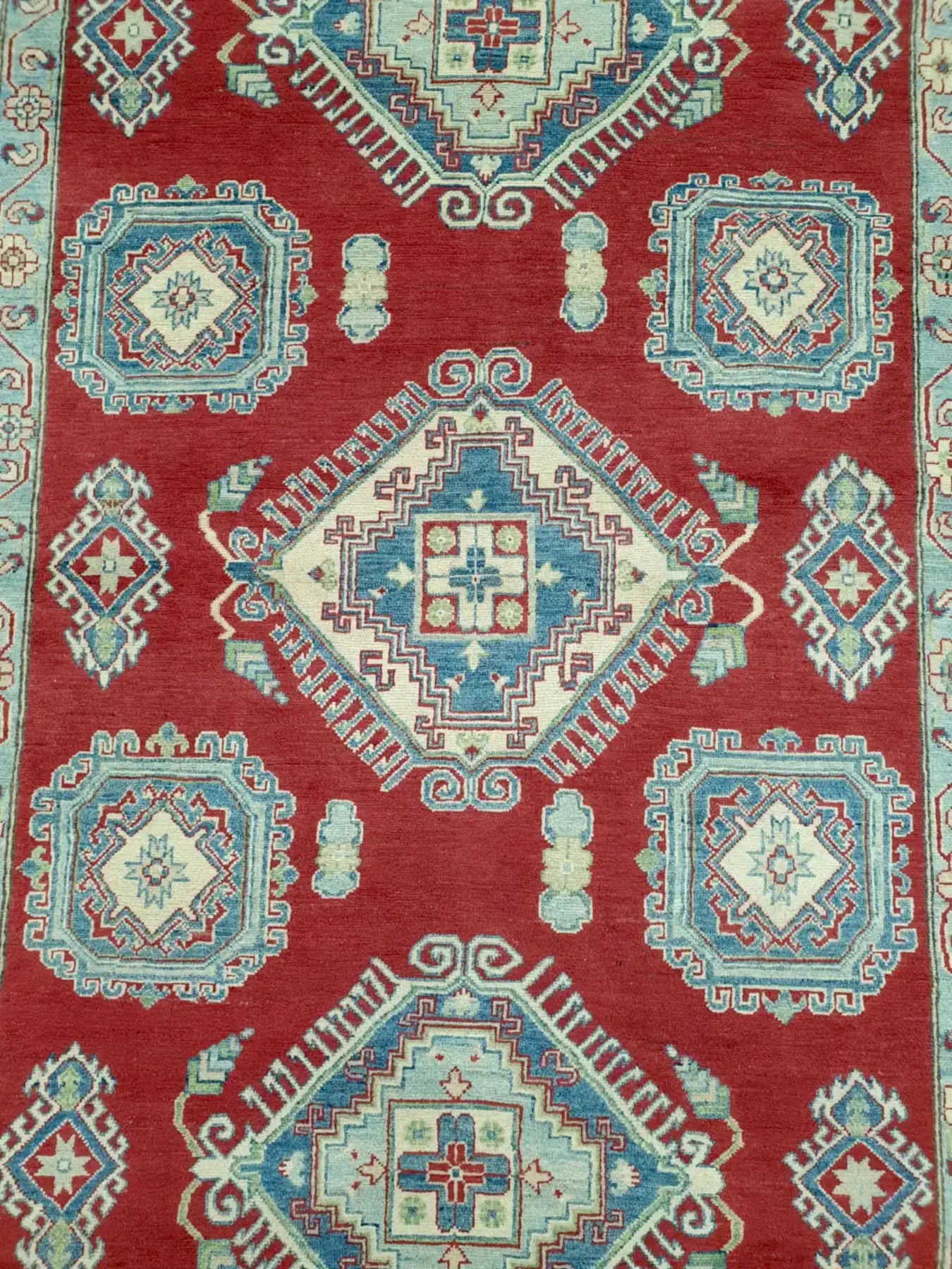 Top view of Kazak rug with red, cream and blue geometric medallions