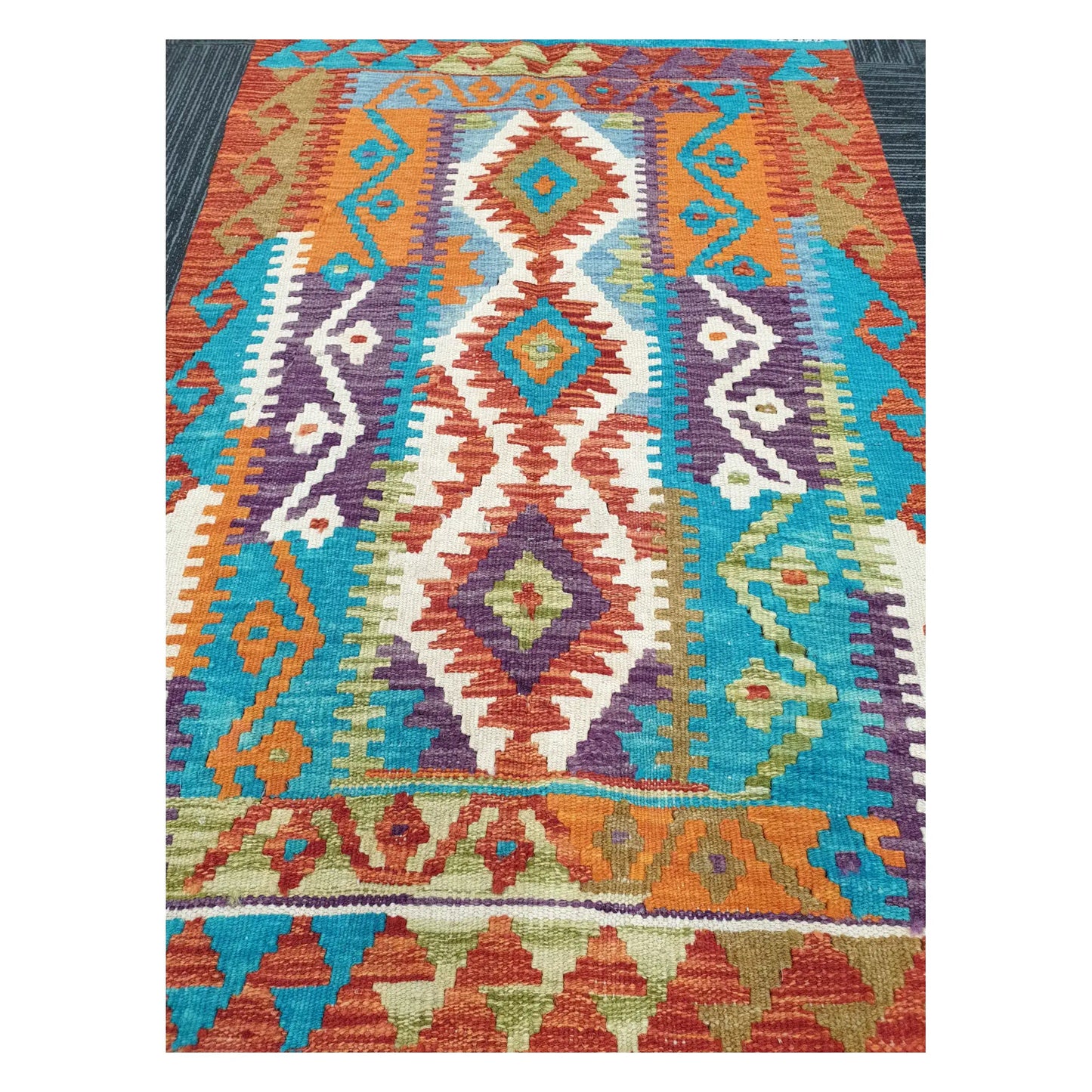 Close-up of Chobi Kilim rug with stacked diamond motifs in turquoise, plum, rust orange, and ivory, 113 x 89 cm