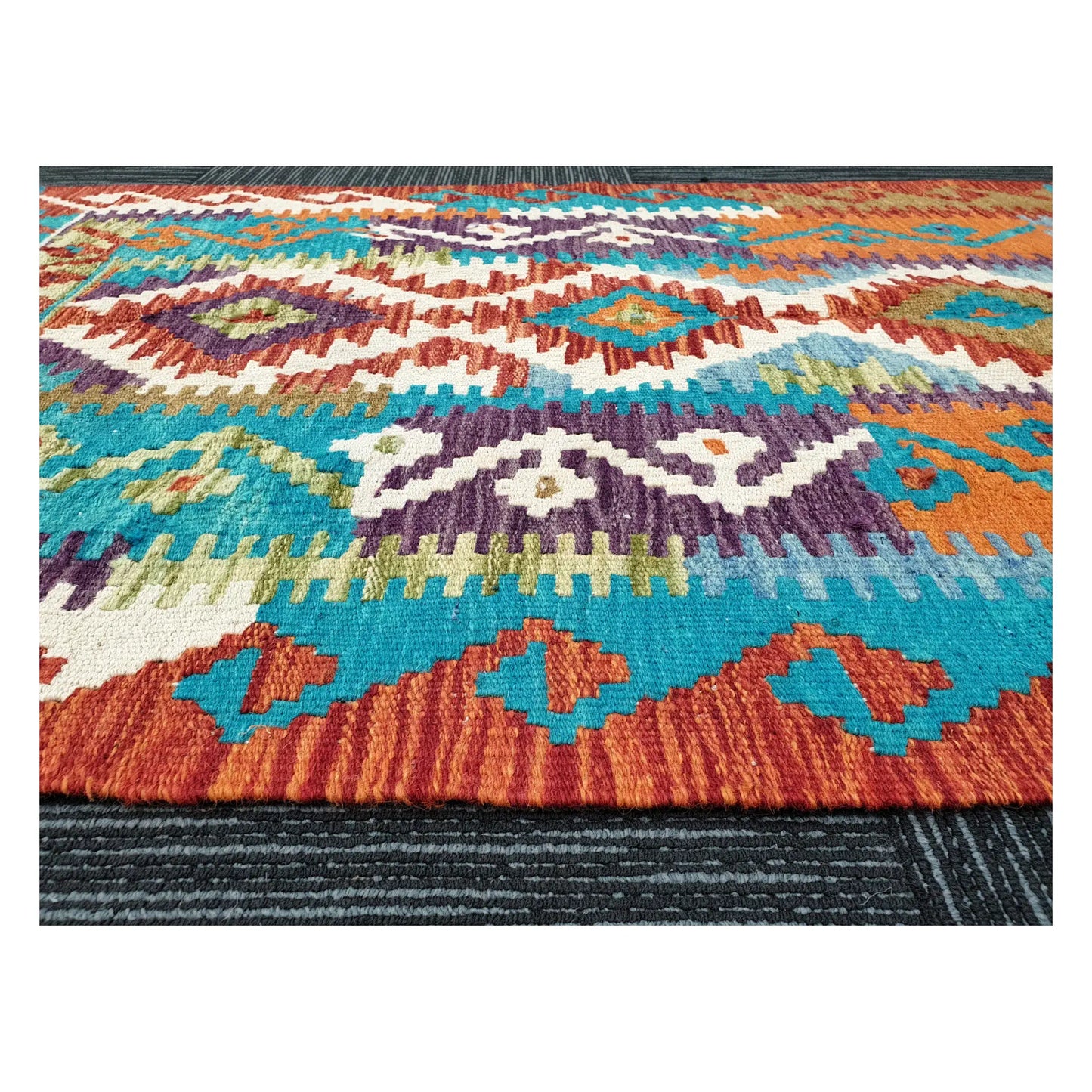 Low-angle close-up of Afghan Chobi Kilim showing wool flatweave texture and geometric tribal pattern, 113 x 89 cm