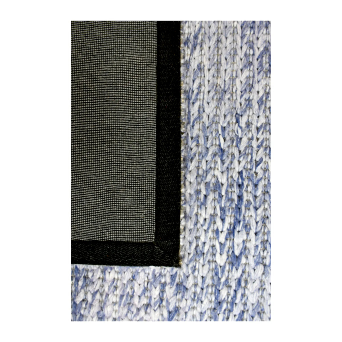 Folded-corner detail of Harlow hand-tufted wool rug showing the dark fabric backing beside the blue-grey wool pile