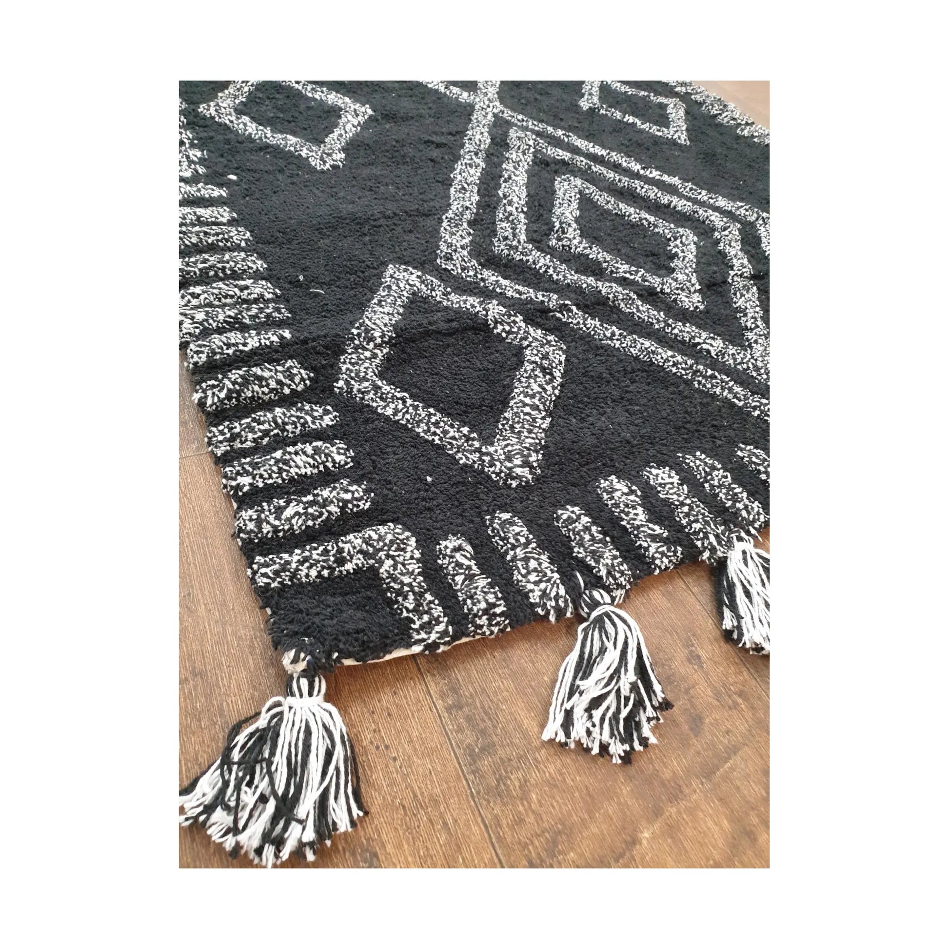 Corner detail of Indian cotton black diamond rug showing tasselled edge and texture