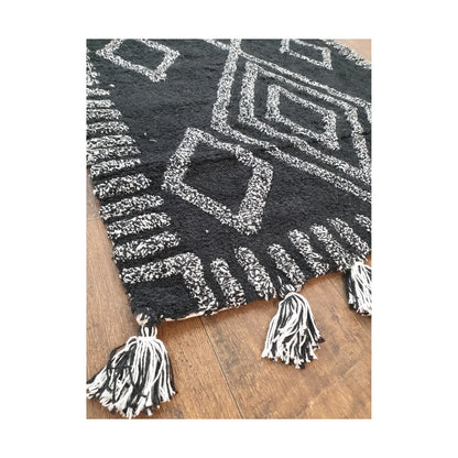 Corner detail of Indian cotton black diamond rug showing tasselled edge and texture