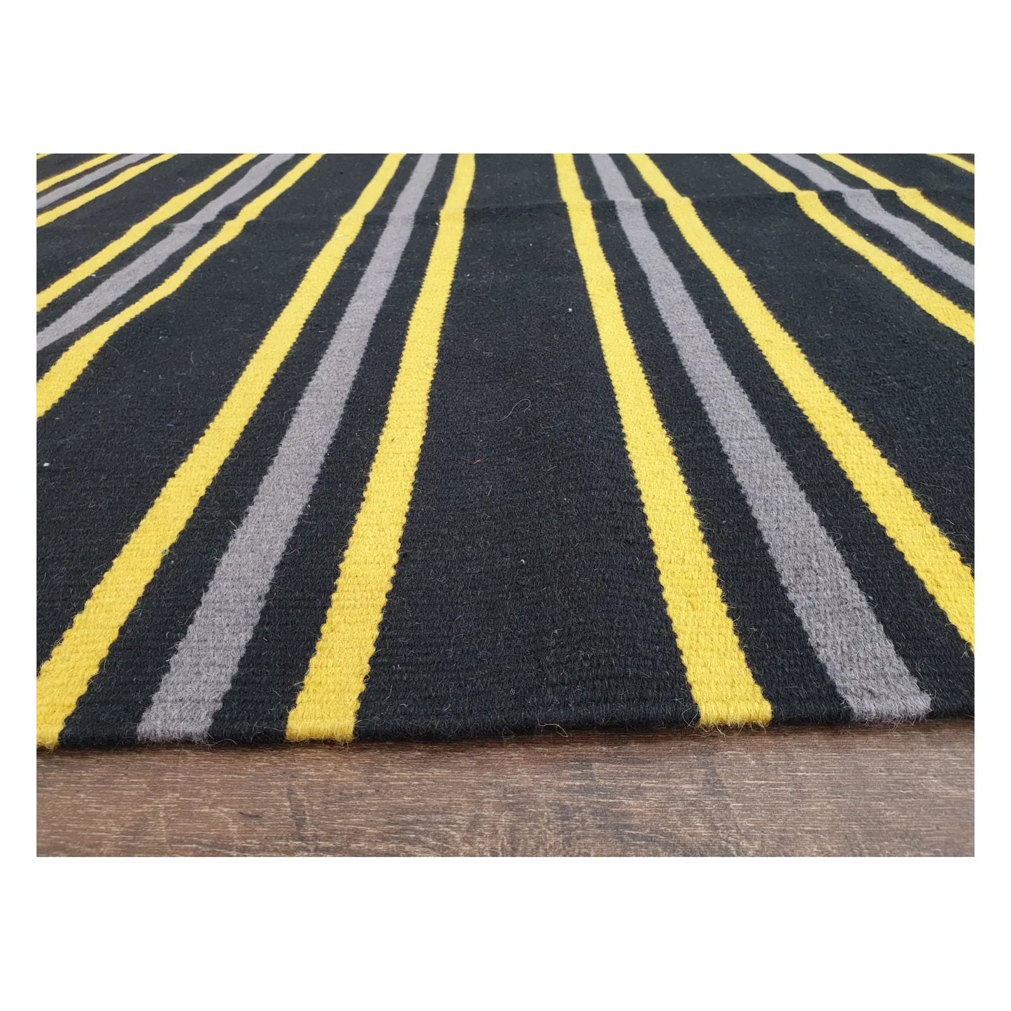 Low-angle close-up of Indian Dhurrie fine wool rug showing striped flatweave texture in charcoal, yellow, and grey, 230 x 160 cm