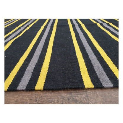 Low-angle close-up of Indian Dhurrie fine wool rug showing striped flatweave texture in charcoal, yellow, and grey, 230 x 160 cm
