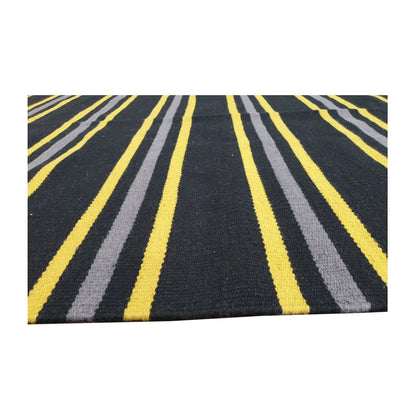 Low-angle close-up of Indian Dhurrie fine wool rug showing striped flatweave texture in charcoal, yellow, and grey, 230 x 160 cm