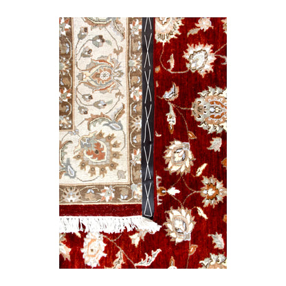 Folded-corner detail of Indian Ziegler rug showing the patterned reverse beside its red floral front and white fringe