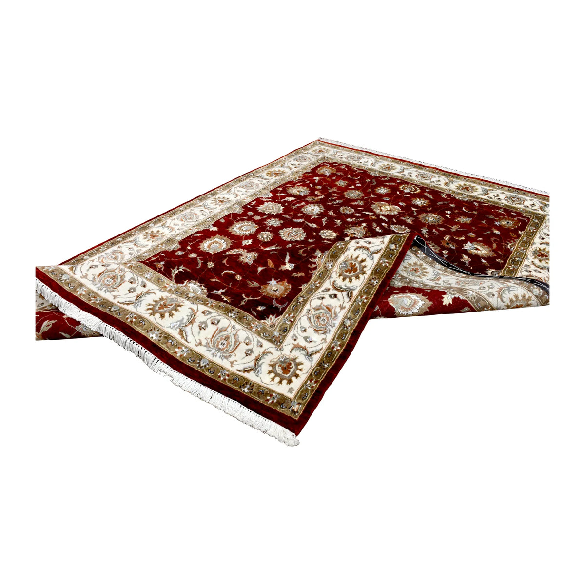Folded view of Indian Ziegler rug showing its red floral surface, ivory border and white fringe