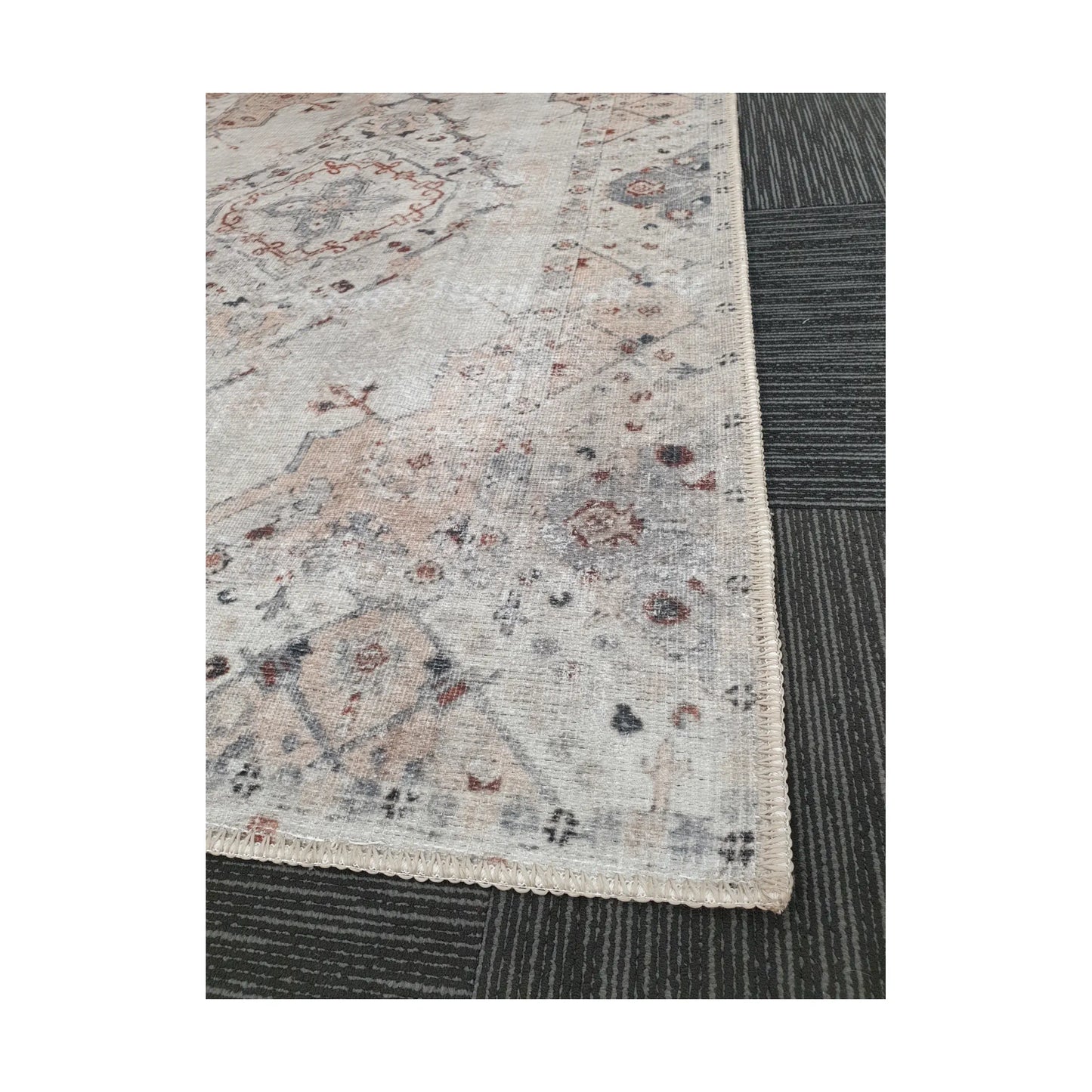 Close-up of ivory blush cotton rug corner with faded floral border detail