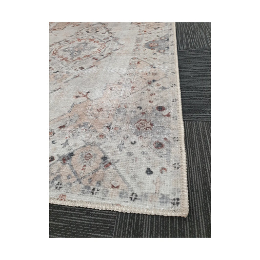 Close-up of ivory blush cotton rug corner with faded floral border detail