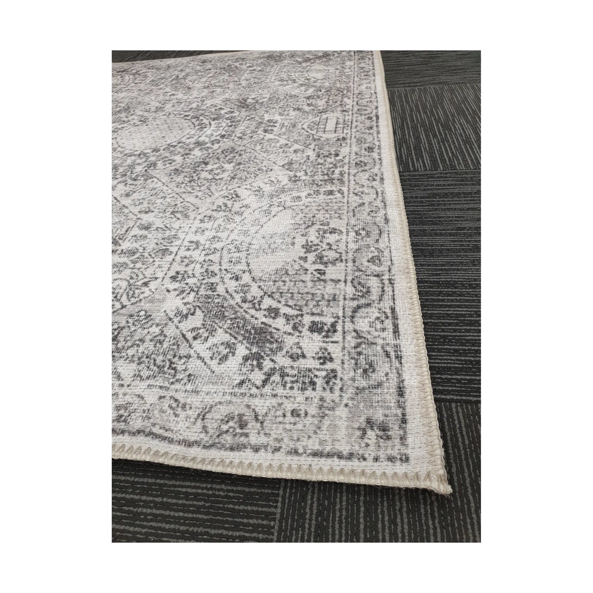 Close-up of ivory grey cotton rug corner with floral border detail