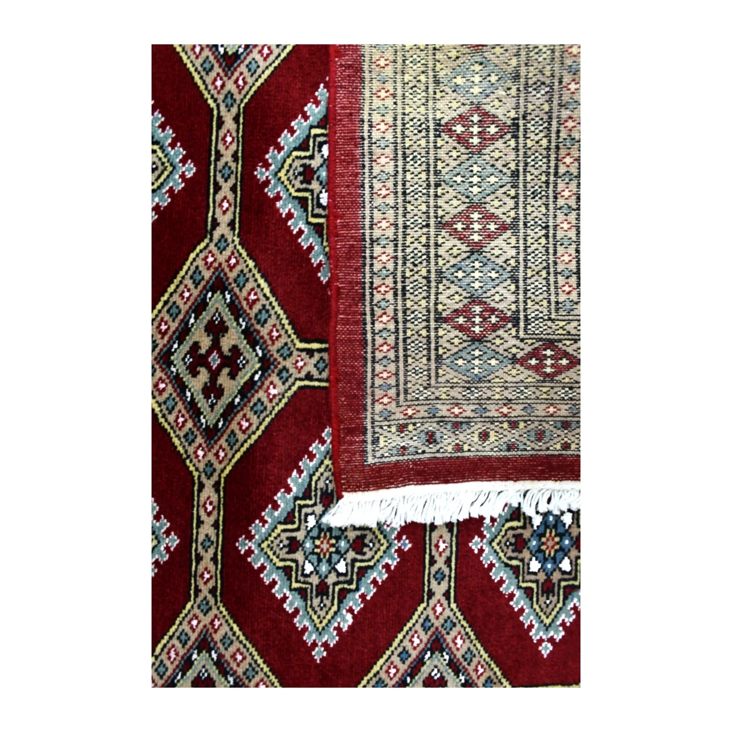 Folded-corner detail of Jaldar rug showing the reverse weave, deep red patterned front and pale fringe
