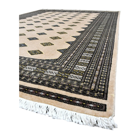 Angled view of Jaldar Silk Touch rug showing its beige diamond-gul field, layered charcoal borders and pale fringe