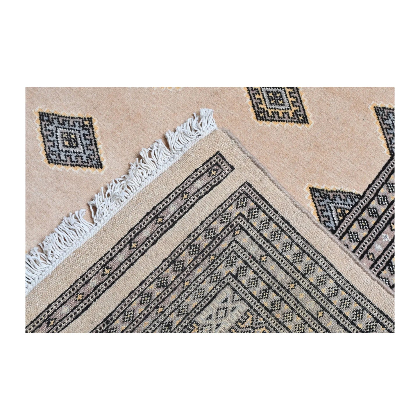 Folded-corner detail of Jaldar Silk Touch rug showing the layered border, beige field, angular gul motifs and visible fringe