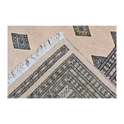 Folded-corner detail of Jaldar Silk Touch rug showing the layered border, beige field, angular gul motifs and visible fringe