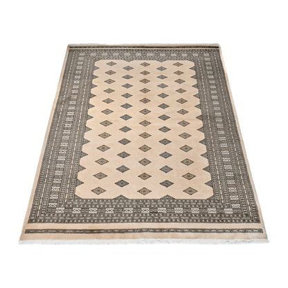 Angled full view of Jaldar Silk Touch wool and silk rug showing the beige field, repeating diamond guls and patterned borders