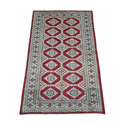 Angled full view of Jaldar wool rug showing the repeating angular guls, red field and layered geometric borders
