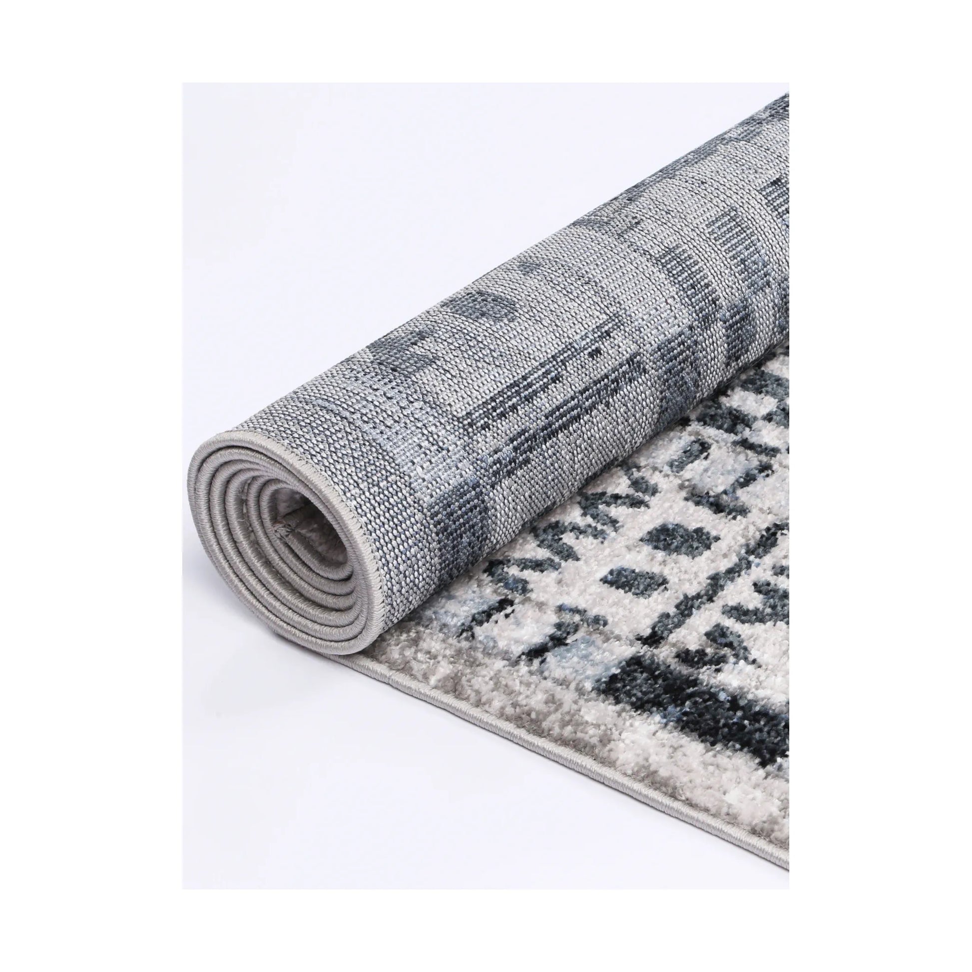 Rolled edge detail of Kimberley 7 Aztec Blue rug showing backing, binding and patterned heatset polypropylene pile, 230 x 160 cm