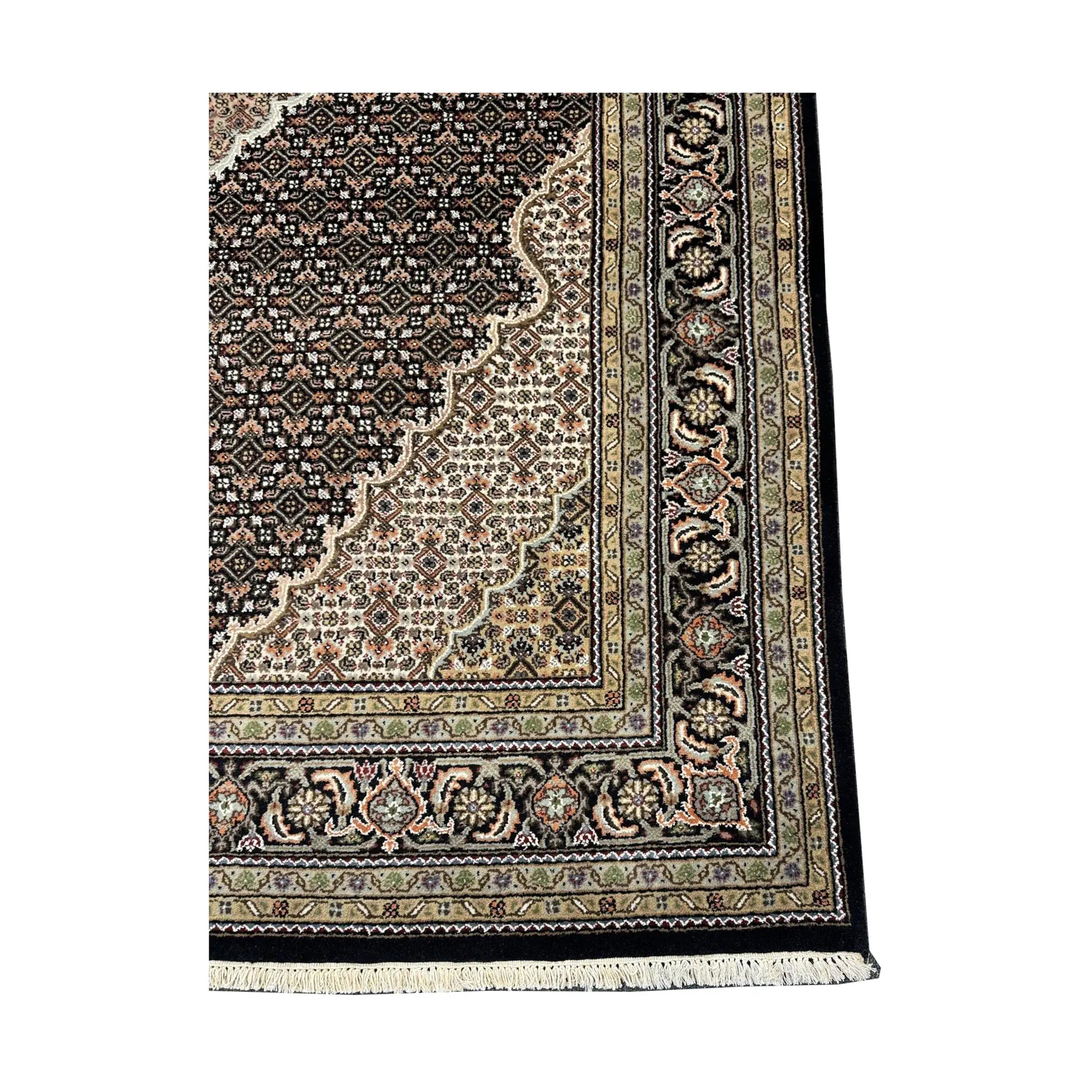 Corner detail of Mahi Tabriz rug showing the dense field pattern, layered floral border and visible fringe edge
