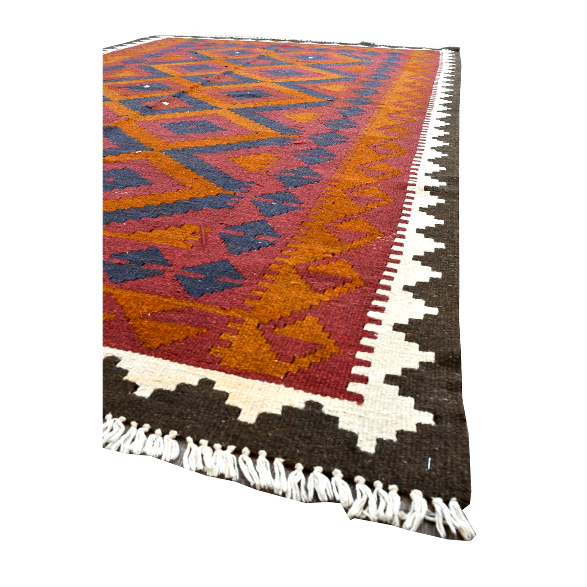 Angled detail of Mamina kilim showing geometric border bands, the pointed ivory and dark brown outer frame and pale fringe