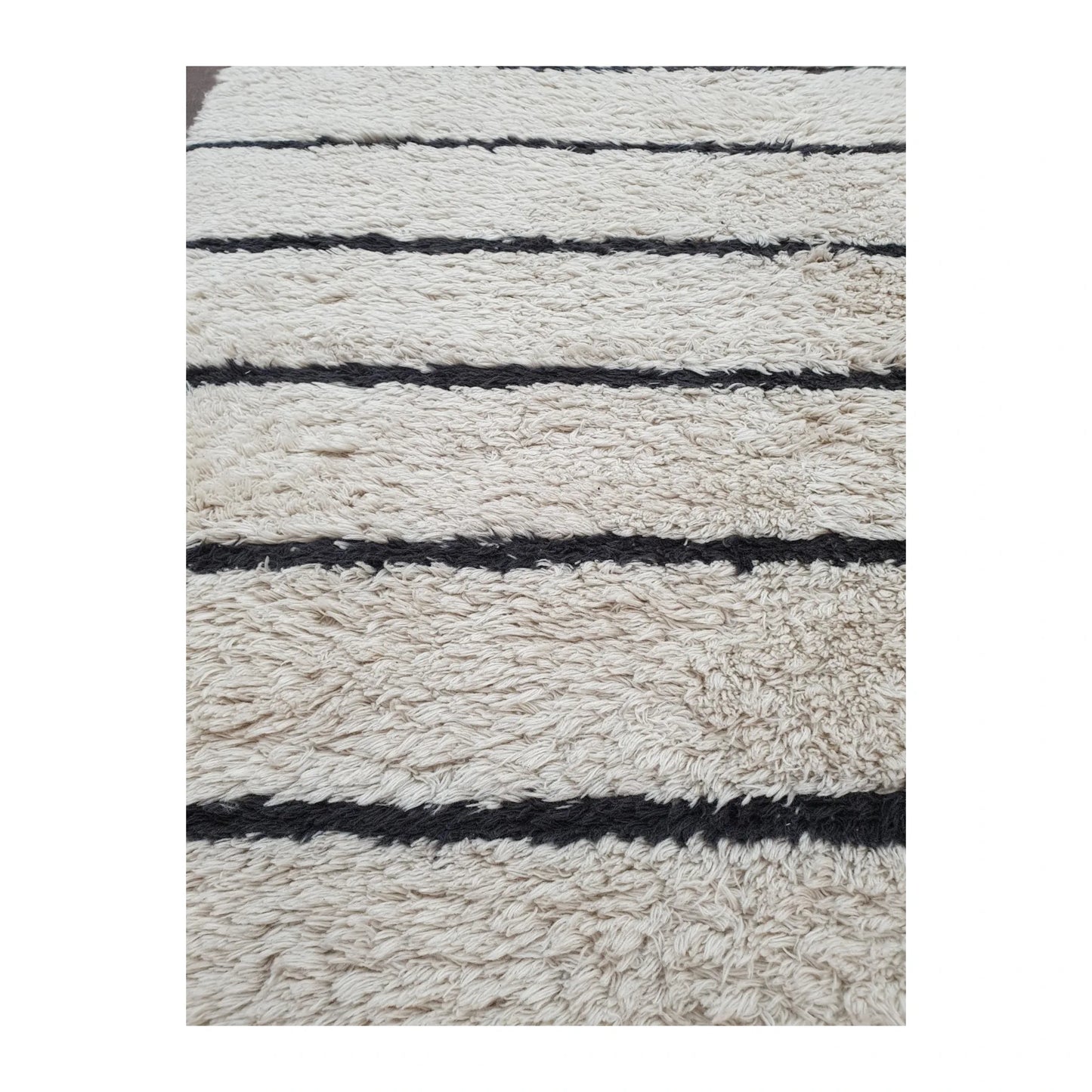 Detail of Moroccan Design hand-knotted wool rug showing textured cream wool pile and irregular black stripe pattern, 165 x 90 cm
