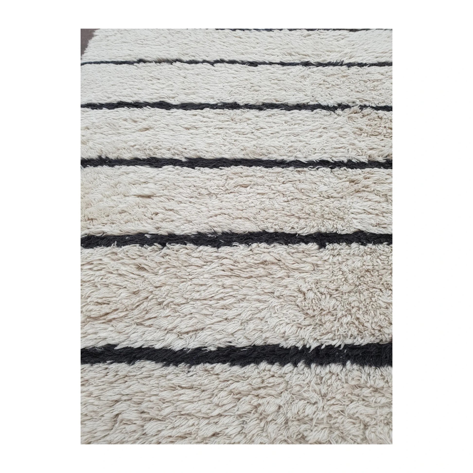 Detail of Moroccan Design hand-knotted wool rug showing textured cream wool pile and irregular black stripe pattern, 165 x 90 cm