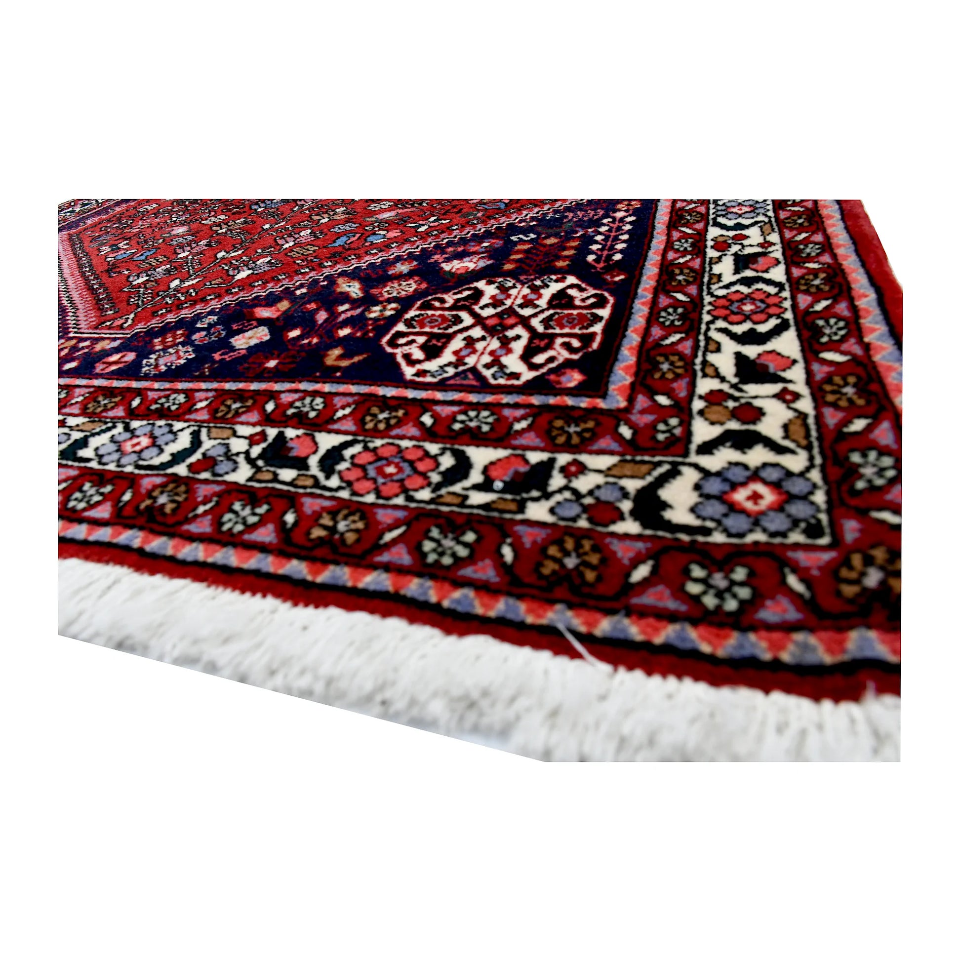 Angled corner and fringe view of Persian Abadeh wool rug showing border detail, red field and light fringe