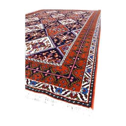 Angled view of Persian Afshar wool rug showing its diamond lattice field, layered borders and pale fringe