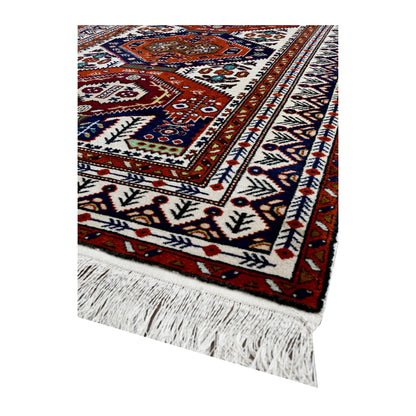 Angled corner of Persian Ardabil rug showing layered geometric borders and ivory fringe