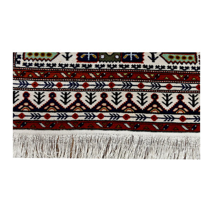 End detail of Persian Ardabil rug showing the rust-red border, repeating geometric motifs and ivory fringe