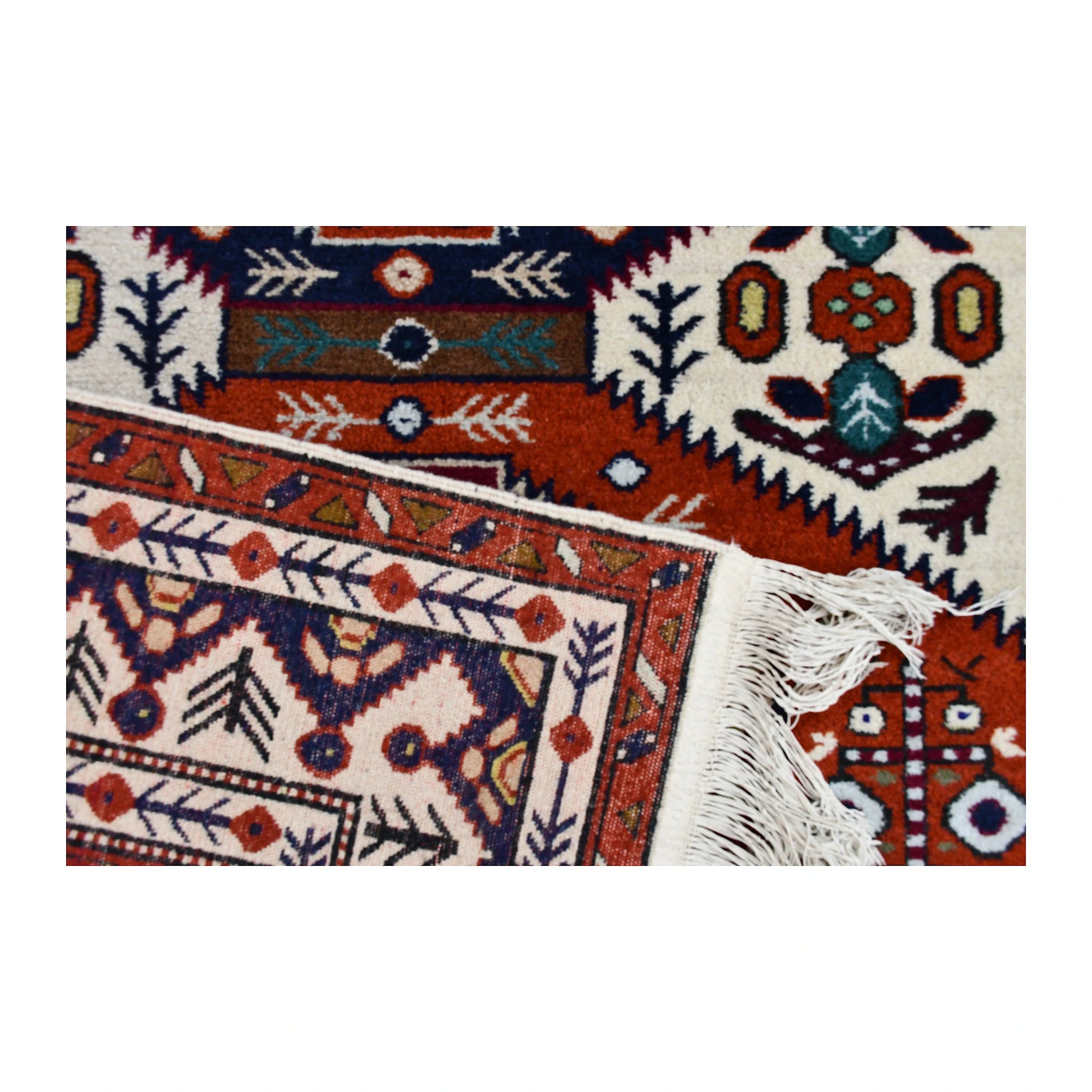 Folded corner of Persian Ardabil rug showing the patterned face, reverse weave and ivory fringe
