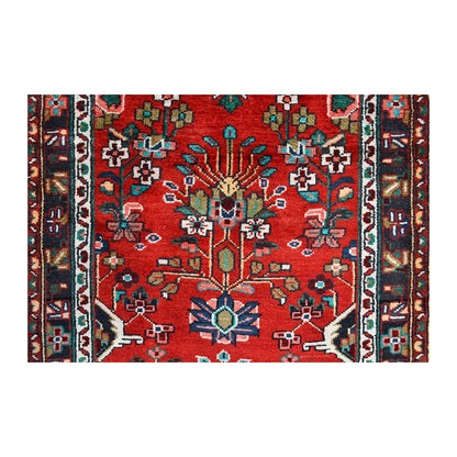 Field close-up of Persian Hamadan runner showing an angular flowering stem and small multicoloured blossoms