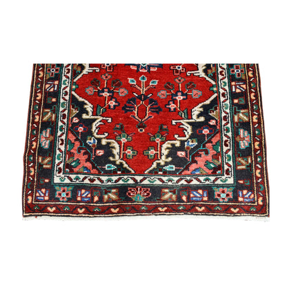 End detail of Persian Hamadan runner showing a floral medallion, branching motifs, layered borders and fringe