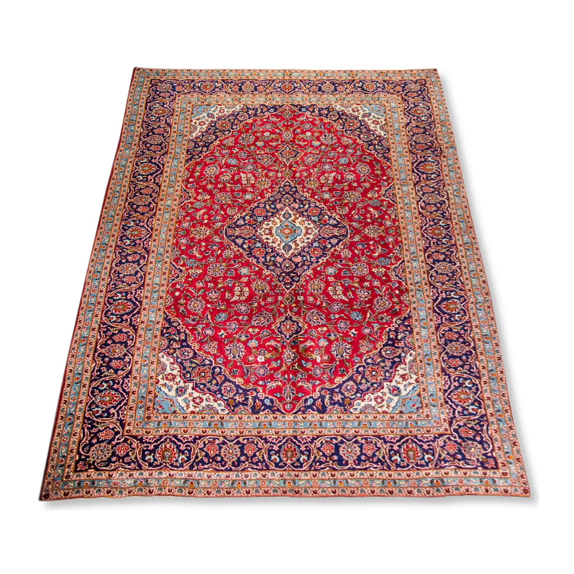 Angled full view of Persian Kashan wool rug showing red medallion field, ornate border and hand-knotted pile