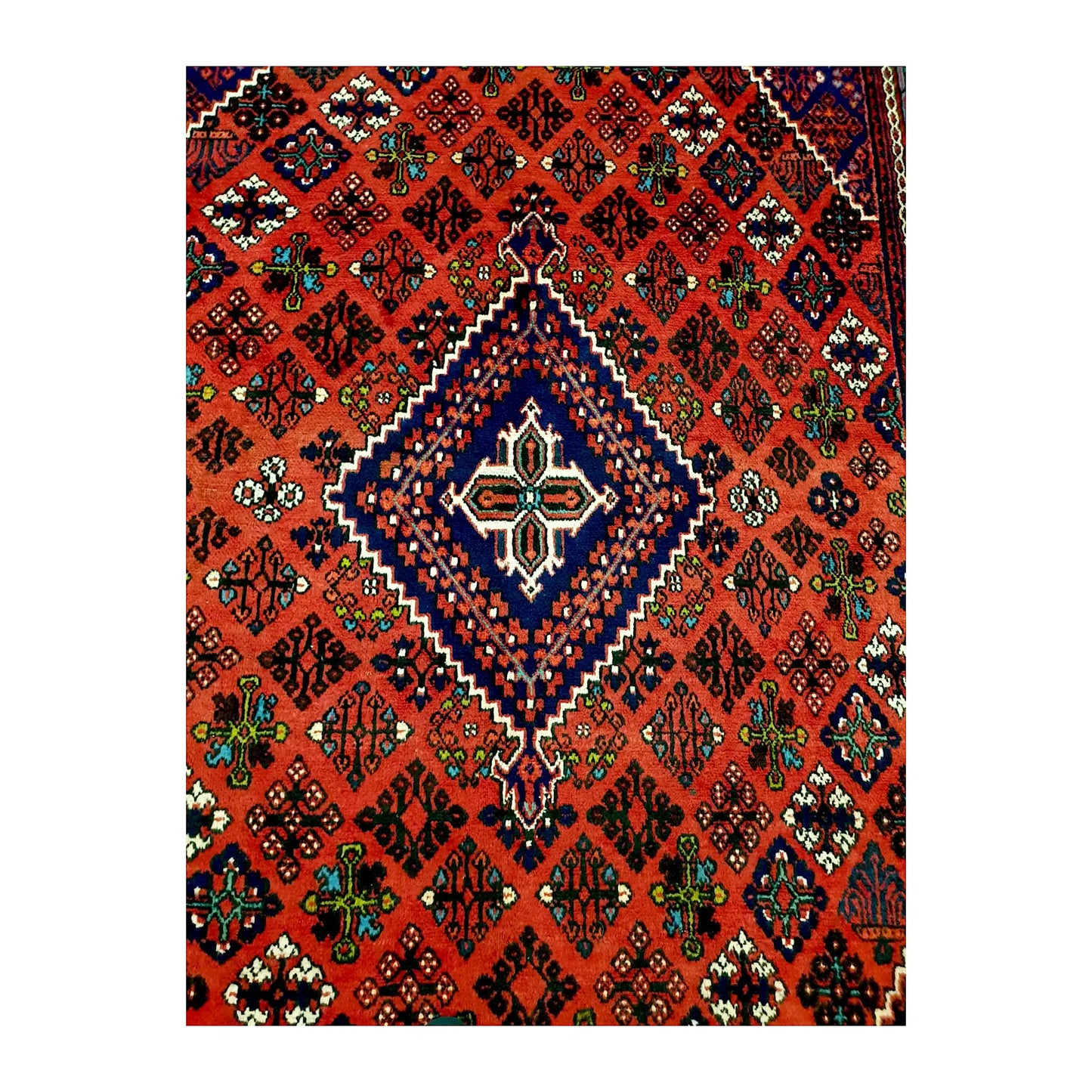 Close view of the stepped navy diamond medallion and multicoloured geometric motifs on the red field